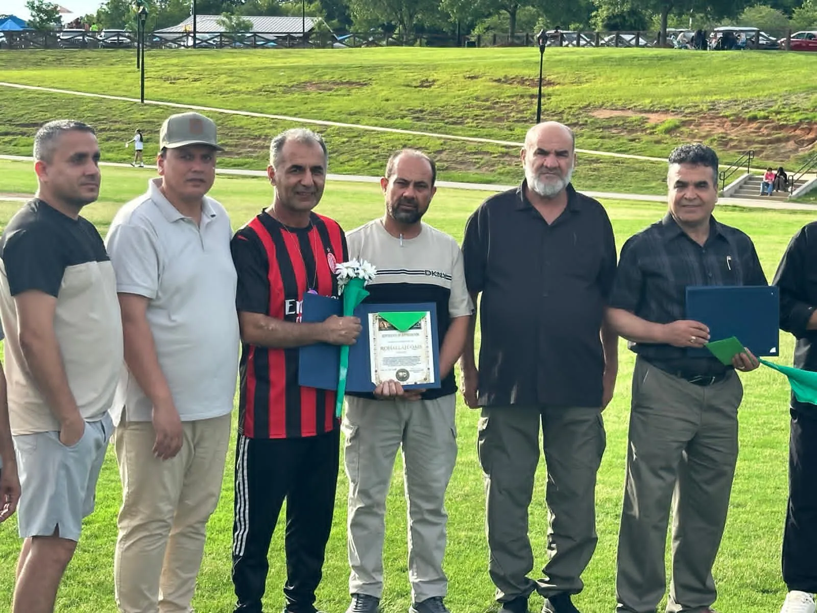Community members holding certificates together at a Maihan Association recognition event.