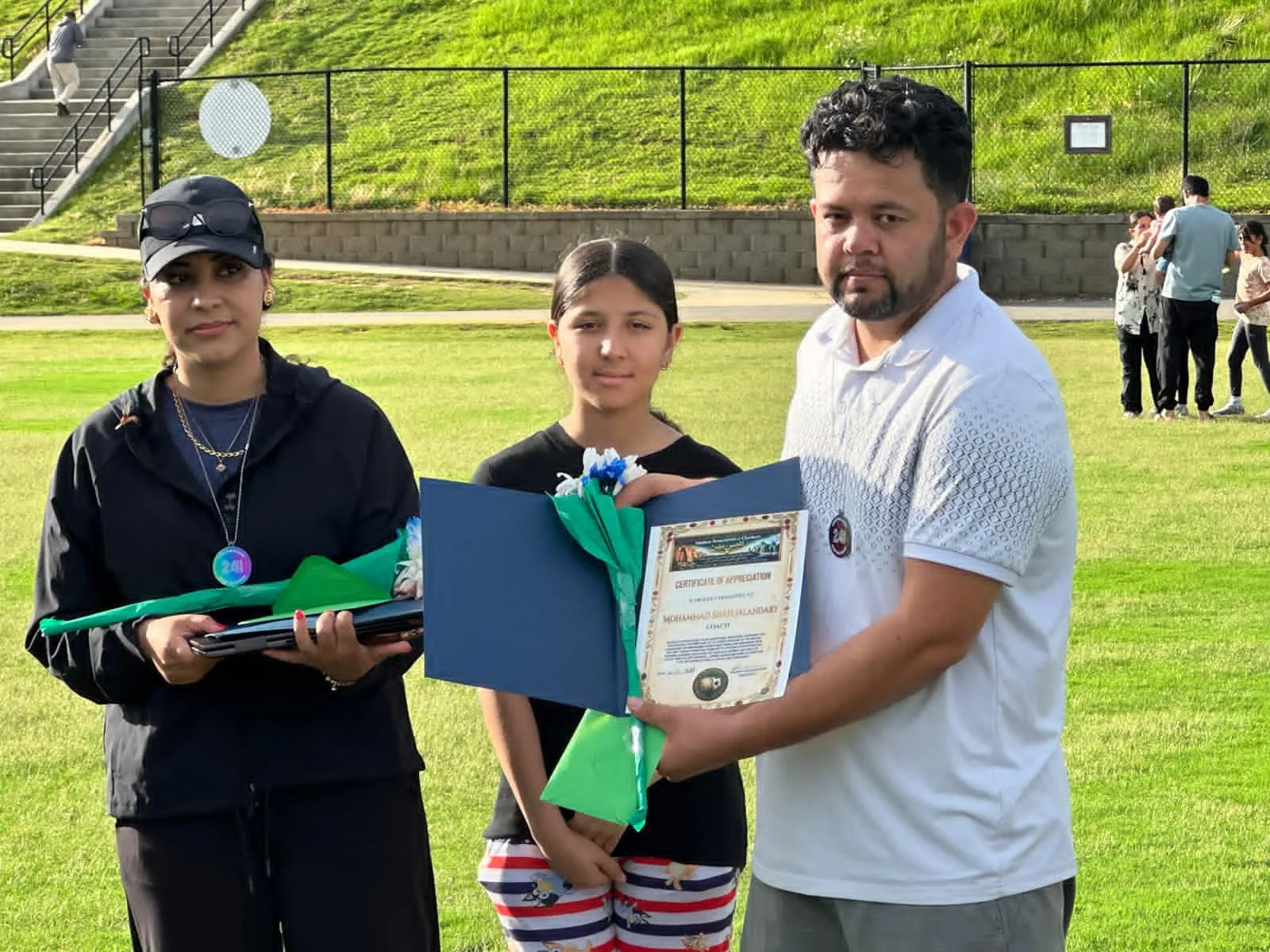 A family receiving a certificate at a Maihan Association recognition event.
